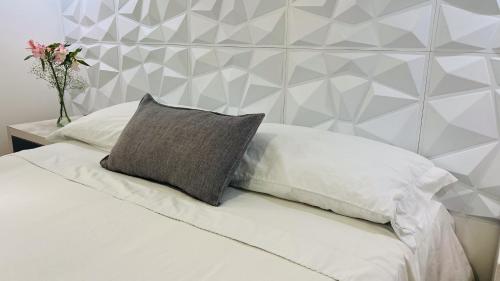 a white bed with a pillow and a wall at Kromatic Hostel in Medellín