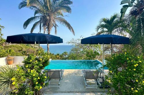 een zwembad met stoelen en parasols en de oceaan bij Sunny 2-Story Loft w Ocean Views & Infinity Pool! in Sayulita