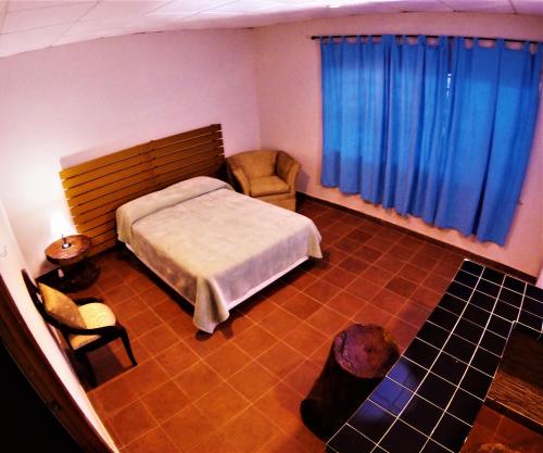 a bedroom with a bed and a chair and blue curtains at Hacienda Alajuela in Colón