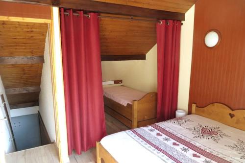 ein kleines Schlafzimmer mit roten Vorhängen und einem Bett in der Unterkunft Appartement serre chevalier 1200 in Briançon