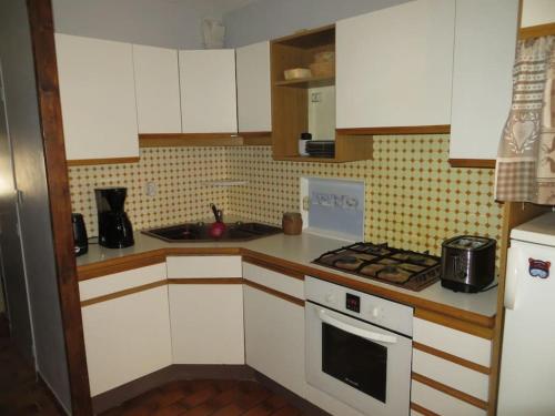 une cuisine avec des armoires blanches et un four à plaques de cuisson dans l'établissement Appartement serre chevalier 1200, à Briançon