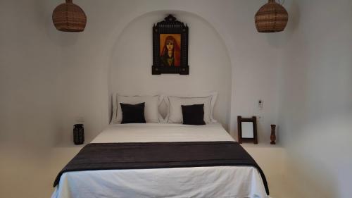 a bedroom with a white bed with black pillows at Maison d’hôte, Djerba 