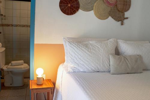 a bedroom with a white bed with a toilet and a lamp at Pousada Sabina in Barra Grande