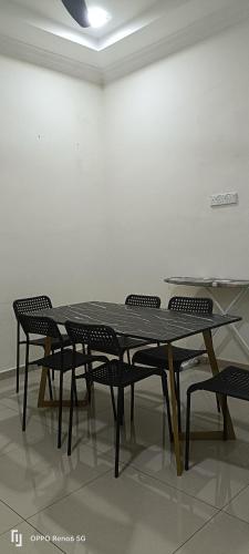 een tafel en stoelen in een kamer met een witte muur bij Rawynaa Segamat Homestay 