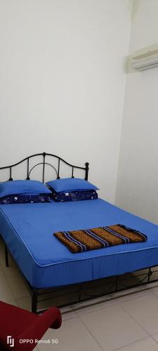 een bed met blauwe lakens en blauwe kussens erop bij Rawynaa Segamat Homestay 