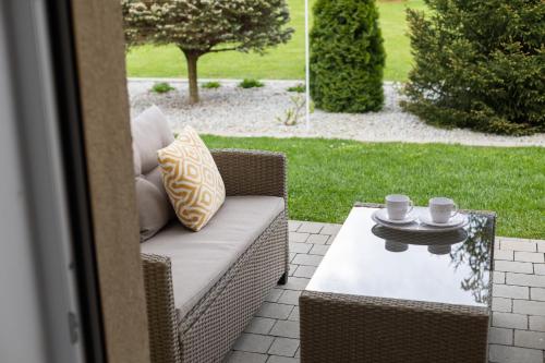 a wicker chair and a table on a patio at APARTEMENTY ''WERANDA'' z ogrodem w centrum in Kudowa-Zdrój