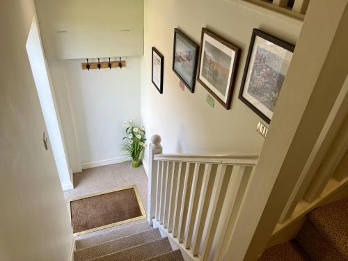 a hallway with a staircase with pictures on the wall at Priors Oak - A Cosy Studio with Countryside Views in Dorset in Stalbridge