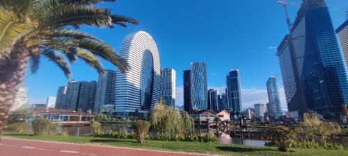 a city skyline with tall buildings and a palm tree at Apart Otel Orbi City in Batumi