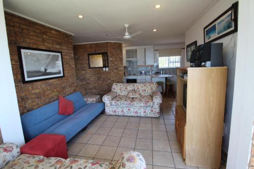 a living room with a blue couch and a kitchen at Providence 79 in Uvongo Beach