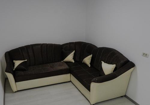 eine schwarze Couch an einer weißen Wand mit Kissen in der Unterkunft Casa Calin in Câmpulung Moldovenesc
