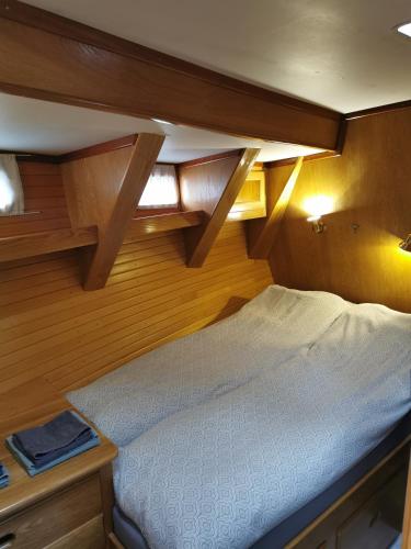 a bed in the corner of a boat with wooden walls at Jolly Good Times Sailing in Tromsø