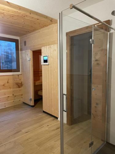 przeszklony prysznic w pokoju z drewnianymi ścianami w obiekcie Golfchalet 3 confini w mieście Tarvisio