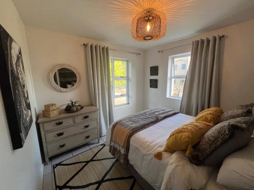 a bedroom with a bed and a dresser and a window at Serenity in Central in Knysna