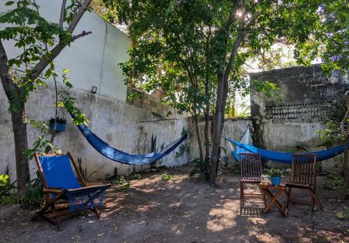 two chairs and a hammock next to a wall at Casa Aguazul in Campeche