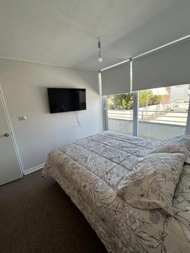 1 dormitorio con 1 cama y TV de pantalla plana en Departamento arriendo Diario Factura Empresas en Talcahuano