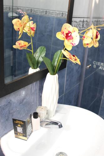 a white vase with flowers on a bathroom sink at Hotel WC in Bogotá
