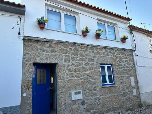 ein Steinhaus mit zwei Fenstern und einer blauen Tür in der Unterkunft 3 Marias São Sebastião in Lousa