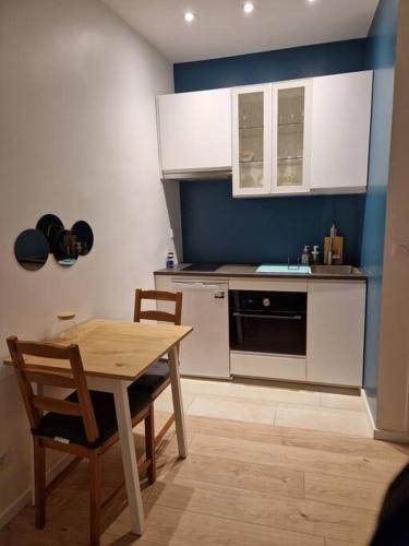 une cuisine avec des armoires blanches et une table et des chaises dans l'établissement Appartement, à Saint-Denis