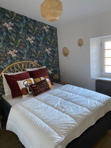 ein Schlafzimmer mit einem großen weißen Bett mit Blumentapete in der Unterkunft Cosy T3 dans corps de ferme l écureuil 