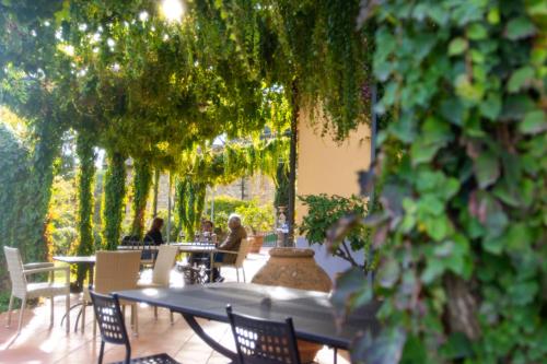 two people sitting at tables in a patio with trees at Tenuta Massabò in San Casciano in Val di Pesa