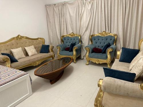 a living room with blue and gold chairs and a table at Sherina Plaza 2 Flat 103 in Dubai
