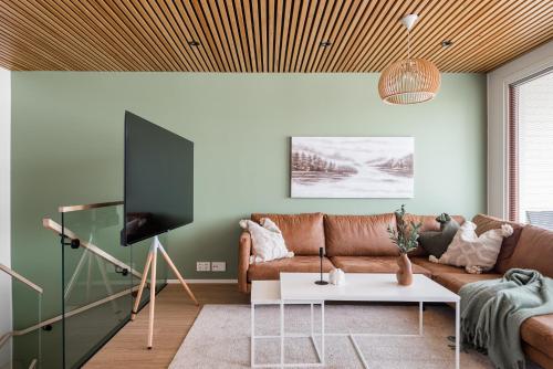 - un salon avec un canapé et une télévision dans l'établissement Kingwest Villa - free parking, sauna & 5 bedrooms, à Tampere