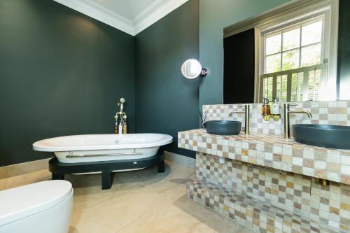 a bathroom with a tub and a sink and a toilet at Hillthorpe Manor by Maison Parfaite - Large Country House with Hot Tub in Pontefract