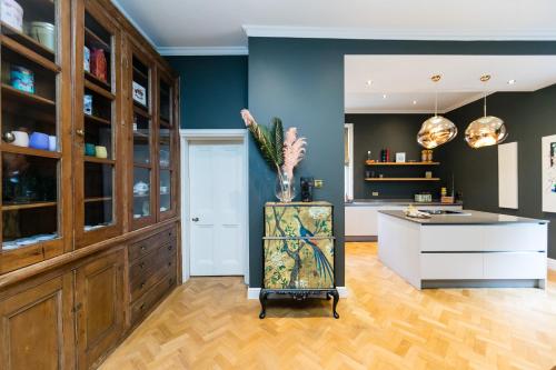 a kitchen with blue walls and a vase of flowers on a counter at Hillthorpe Manor by Maison Parfaite - Large Country House with Hot Tub in Pontefract