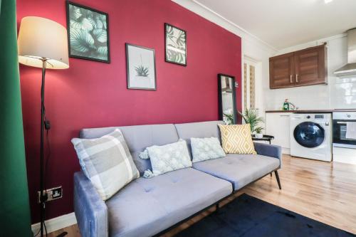 a living room with a blue couch against a red wall at FREE Parking, 1 bedroom apartment close to HEATHROW in Stanwell