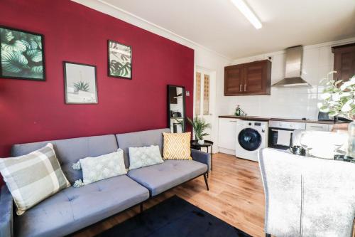 a living room with a couch and a red wall at FREE Parking, 1 bedroom apartment close to HEATHROW in Stanwell