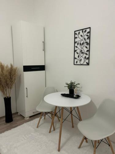 a white dining room with a table and chairs at Central Park Apartment in Novi Sad