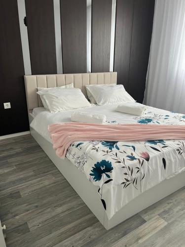 un letto bianco con una coperta floreale sopra di Dielli Apartment New a Pristina