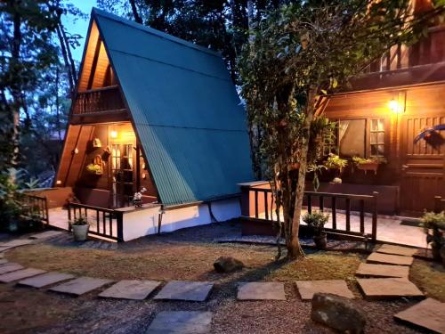 uma casa com um telhado verde e uma árvore em Floresta Encantada em Ubatuba