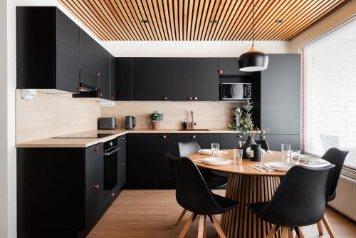 une cuisine avec des armoires noires et une table avec des chaises dans l'établissement Kingwest Villa - free parking, sauna & 5 bedrooms, à Tampere