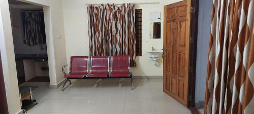 a red chair sitting in a room with a door at Guruvayur Adithya in Guruvāyūr