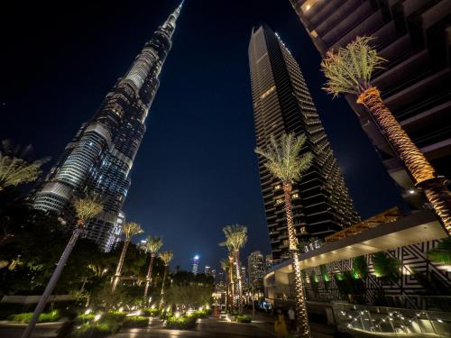 a city with tall buildings and palm trees at night at The Address Residences Dubai Opera , Full Burj Khalifa View , Luxurious 2BR in Dubai