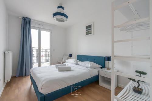 - une chambre blanche avec un lit bleu et une fenêtre dans l'établissement *Disneyland-Paris* 10 pers, Wifi, 2 parkings, à Chessy