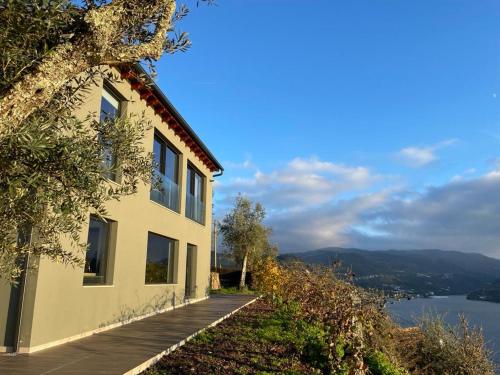 une maison sur une colline à côté d'une masse d'eau dans l'établissement Quinta Vale do Cabo, à Ribadouro