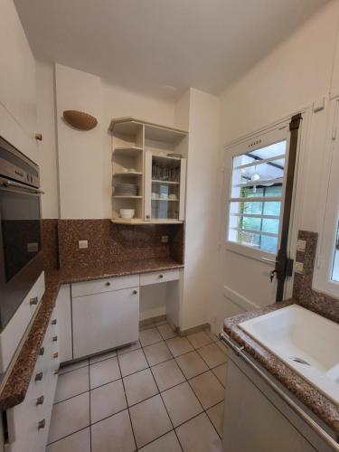 een witte keuken met een wastafel en een raam bij Maison à louer 3 chambres in Sartrouville