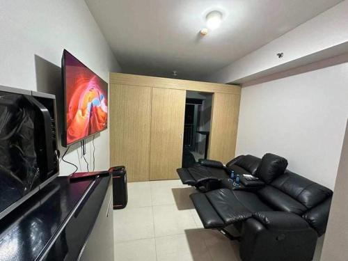 - un salon avec un canapé en cuir noir et une télévision à écran plat dans l'établissement SMDC Grass Residences - Unit # 2816, à Manille