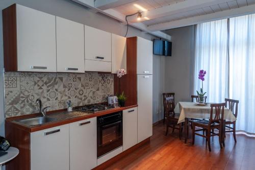 a kitchen with white cabinets and a table with a dining room at Katane Holidays in Catania