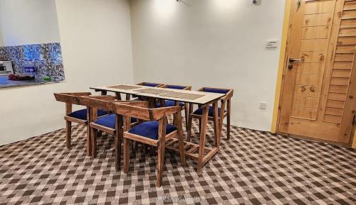 drewniany stół z niebieskimi krzesłami i drewnianymi drzwiami w obiekcie PYRAMID LODGE w mieście Skardu