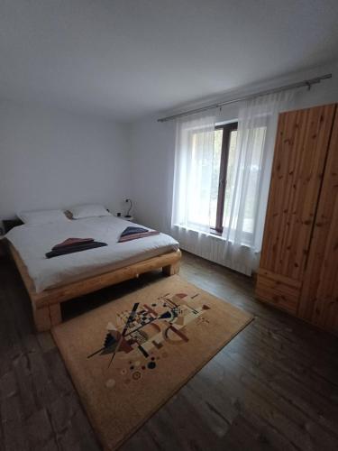 een slaapkamer met een bed, een raam en een tapijt bij House in the Forest in Cătunu