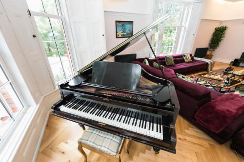 a piano in a living room with a couch at Hillthorpe Manor by Maison Parfaite - Large Country House with Hot Tub in Pontefract