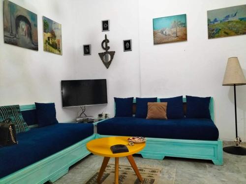a living room with a blue couch and a tv at Dans résidence à bord de la mer avec plage privée in Chott Meriem