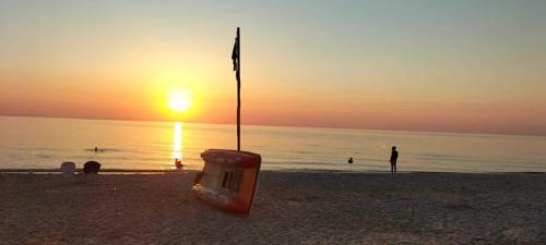 Chott Meriem的住宿－Dans résidence à bord de la mer avec plage privée，海滩上的椅子,背靠日落