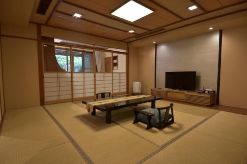 a living room with a table and a tv at Arima Onsen Taketoritei Maruyama in Kobe