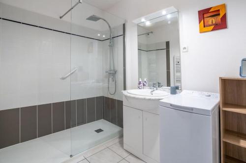 biała łazienka z umywalką i prysznicem w obiekcie Les clés de Jonzacconciergerie Carré des Antilles w mieście Jonzac