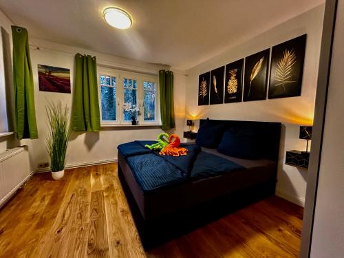 ein Wohnzimmer mit einem schwarzen Sofa und grünen Vorhängen in der Unterkunft Ferienhaus im Grünen mit Kamin in Oranienburg