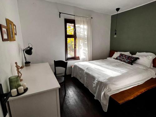 um quarto com uma cama, uma secretária e uma janela em Sentina kuća em Vrtovac